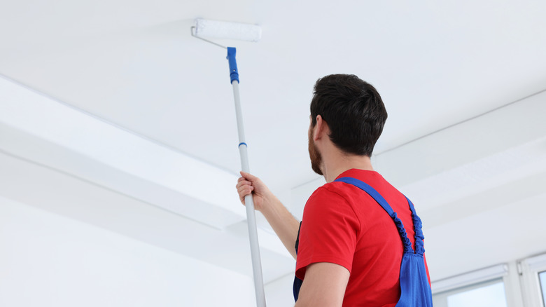 handyman painting ceiling with a paint roller