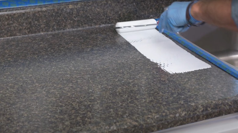 person applying primer paint to laminate countertop