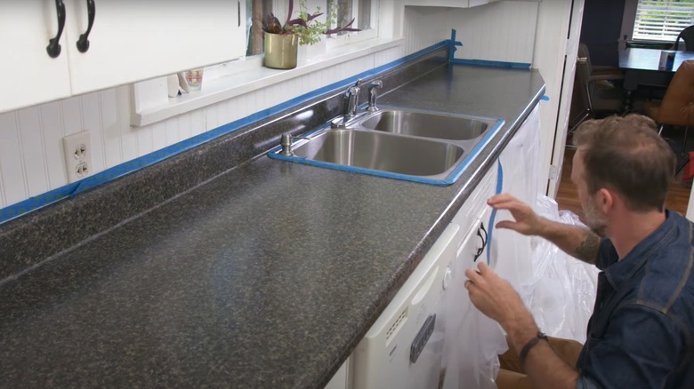 man applying painter's tape near countertop