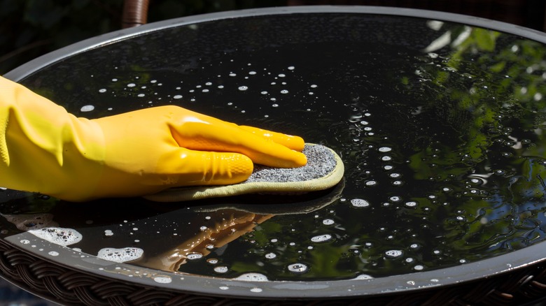 yellow gloved hand wiping table