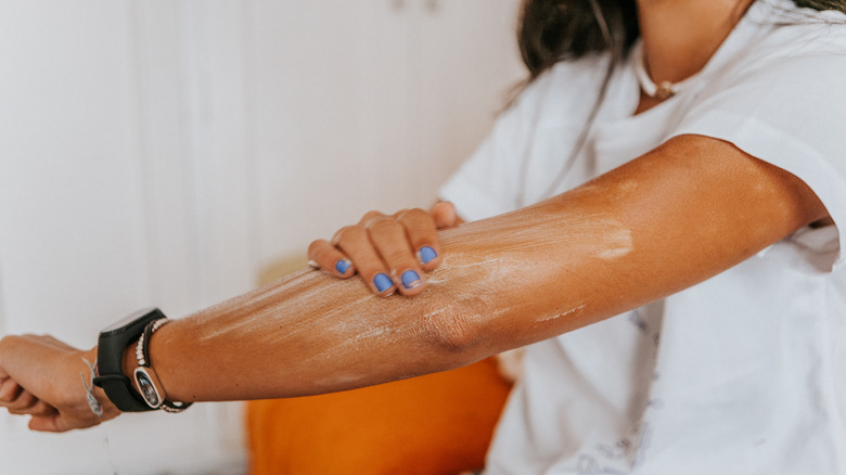 Woman applying suntan lotion on hand