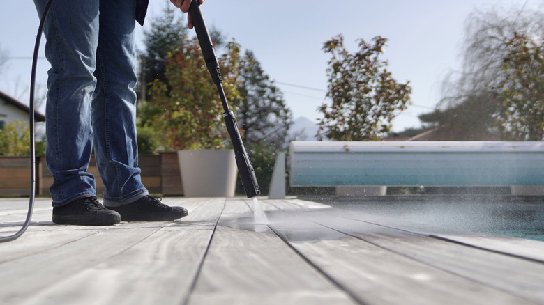 Man cleaning deck with water