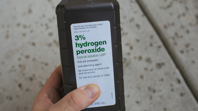 hand holding hydrogen peroxide bottle
