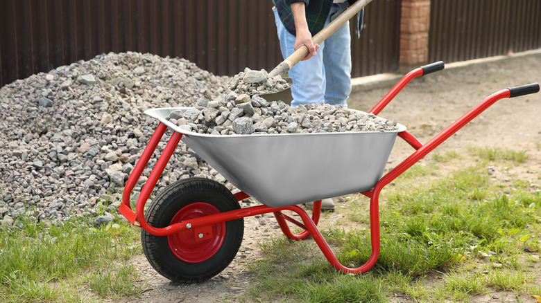 Person loading construction gravel into a wheelbarrow