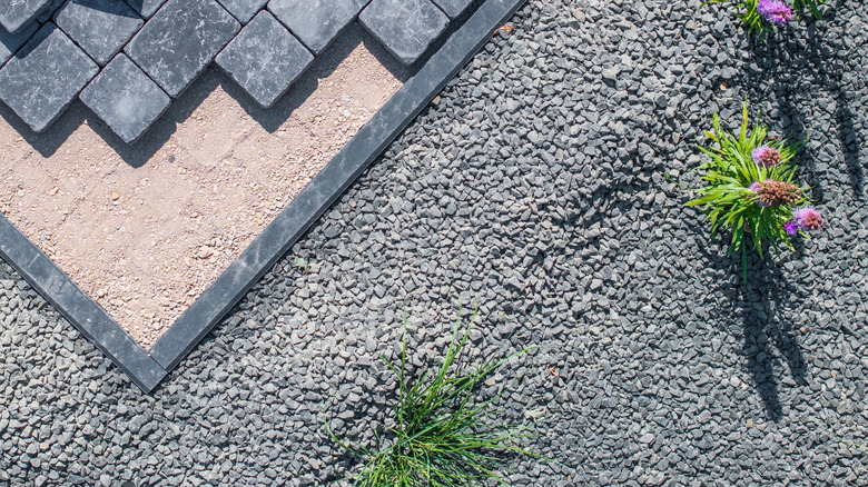 Paving stones being installed in a gravel garden pathway.