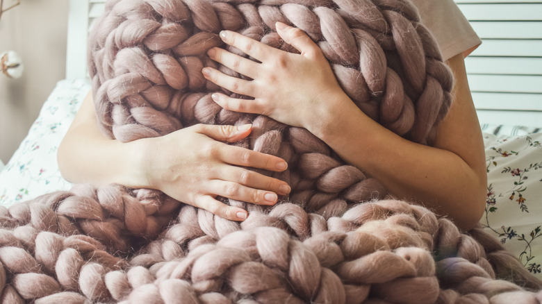 arms hugging chunky wool blanket