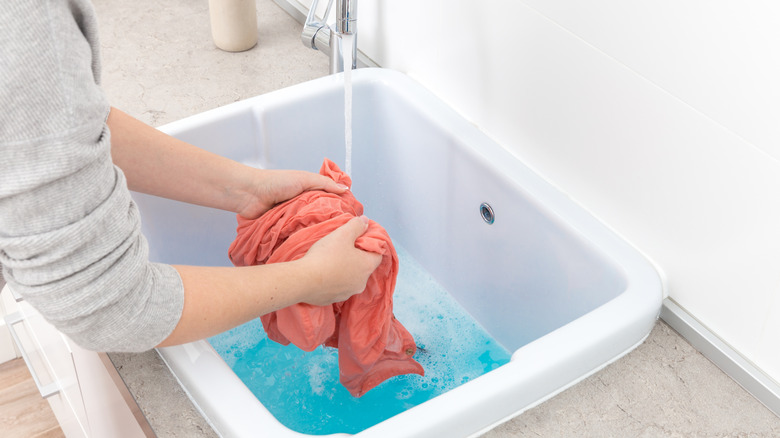 Person rinsing clothing item in sink