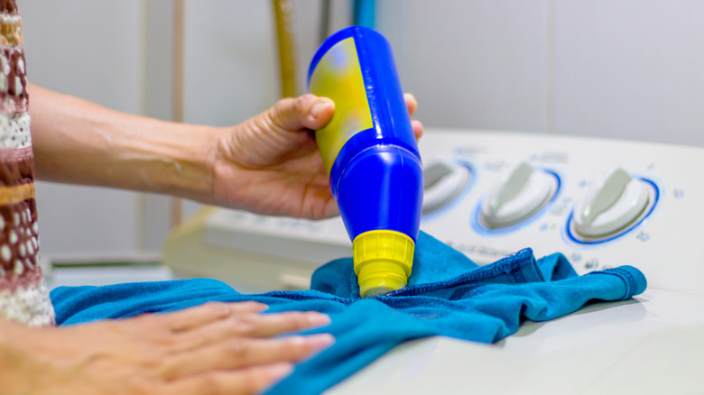 Person using stain remover on blue fabric