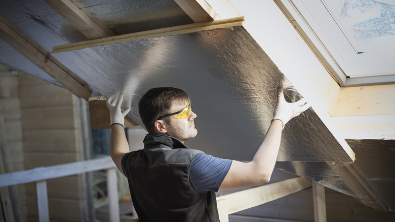 A person installs insulation on the ceiling