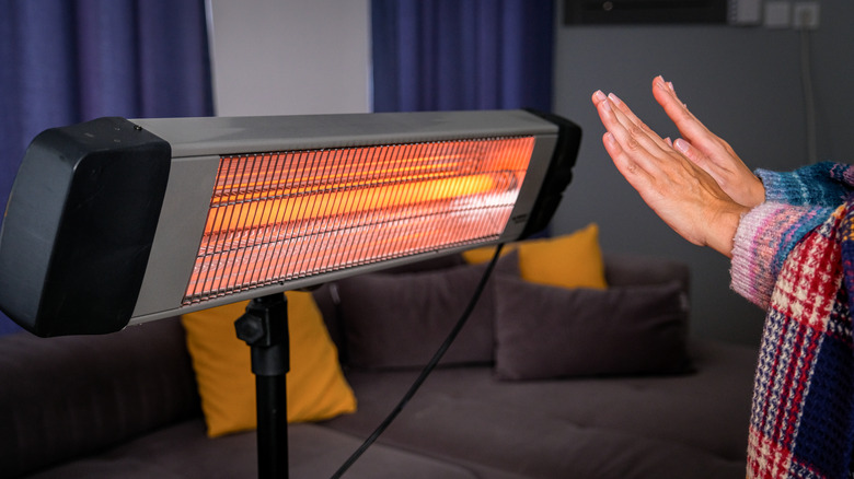 A person using an infrared heater for warmth