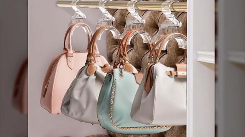 Handbags hanging by clear hooks on a gold rack