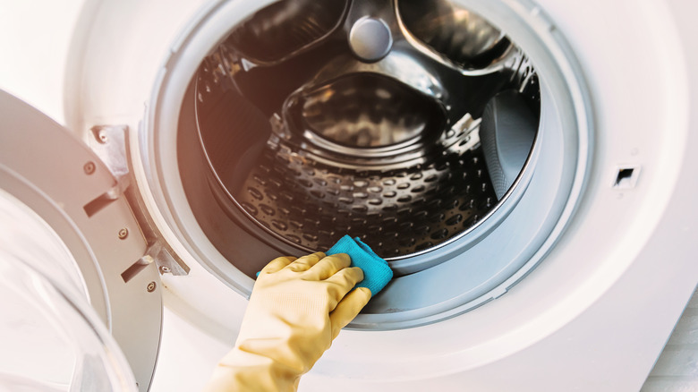 Person scrubbing dirty washing machine