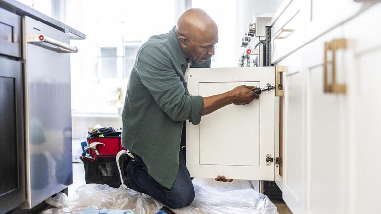 A man installing a kitchen cabinet