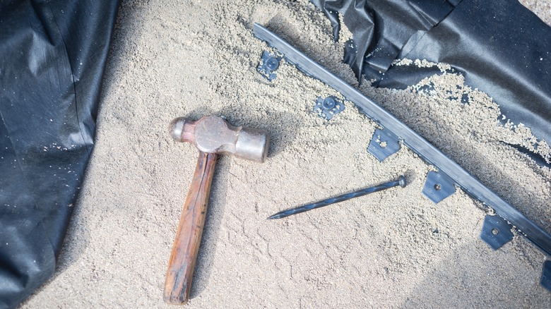 Paver spikes, hammer and nail on ground ready for installation as paver edging