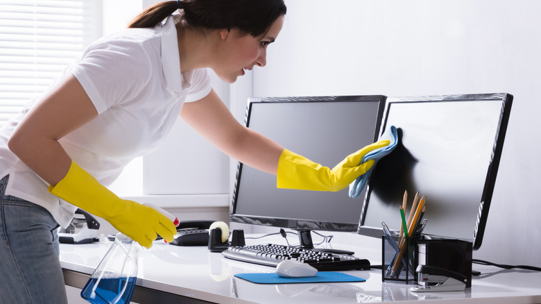 woman cleaning desk with gloves