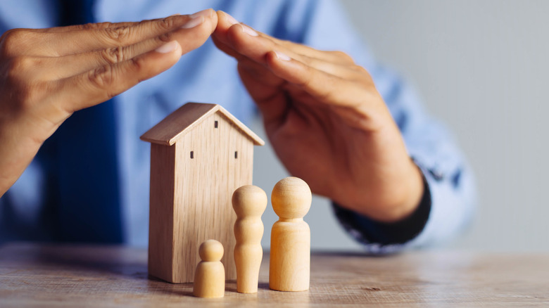 wooden home protected by hands 