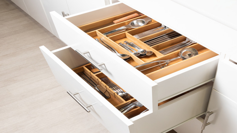 Two open kitchen drawers, filled with silverware