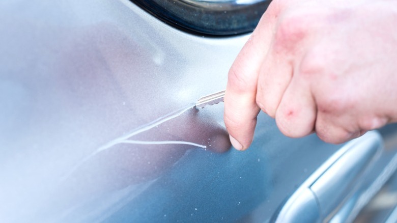 close-up of hand keying door of silver car