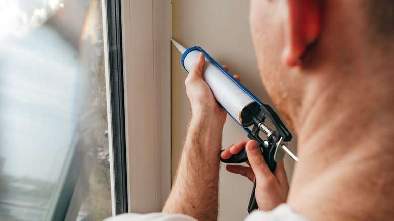 Person sealing grout around window