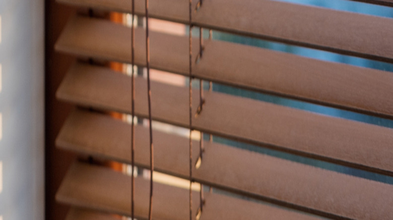 Person opening wooden window blinds