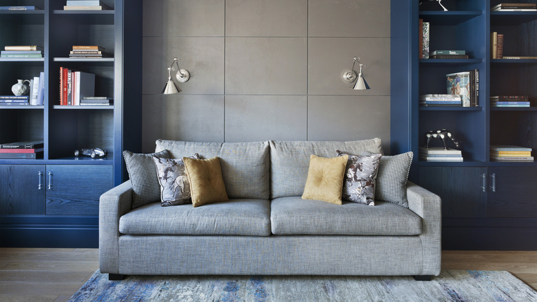 A living room with a gray couch and blue built-in bookshelves