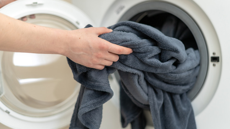 Person pulling gray blanket out of washer