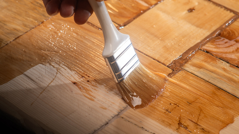 Close-up of someone staining wood using a brush with a white handle