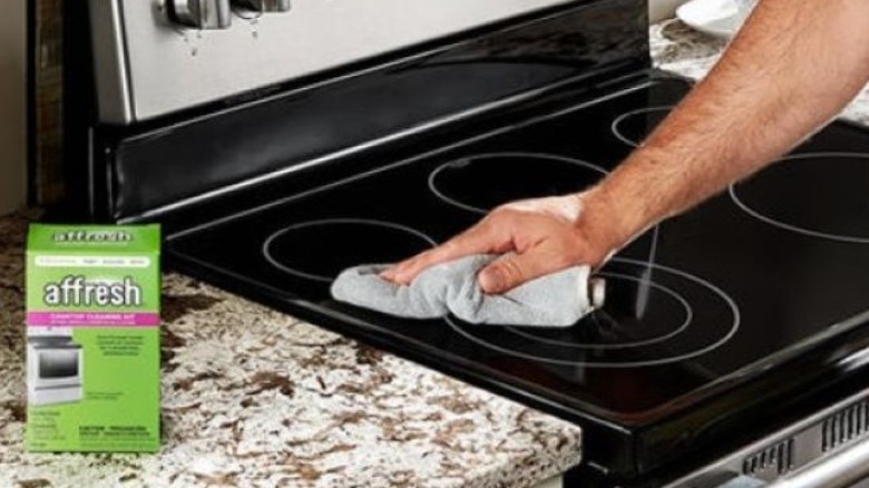 Man cleaning glass stovetop with cloth; box of Affresh