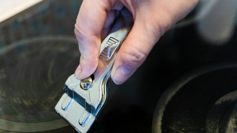 Cleaning glass top stove with razor scraper