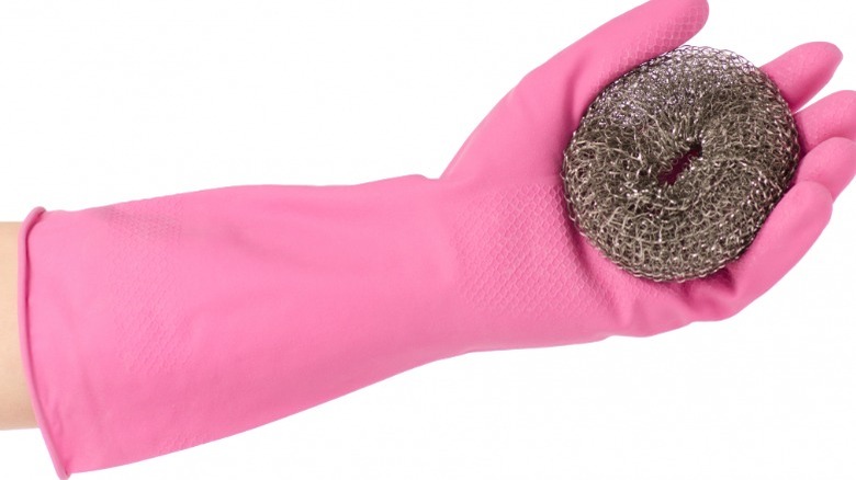 Pink-gloved hand holding steel wool pad