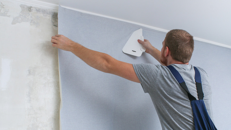 man using squeegee on wallpaper