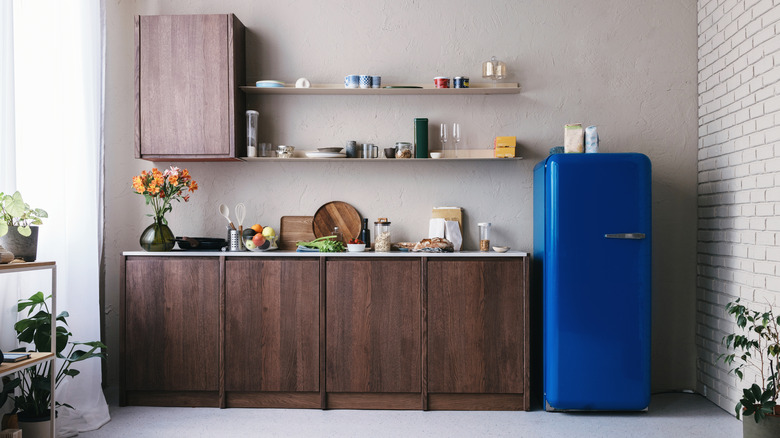 Navy blue fridge in kitchen with wooden cabinets