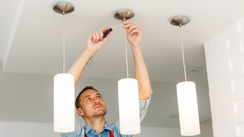 A man installing pendant lights