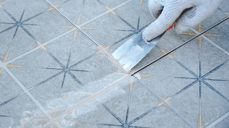 Person filling gaps in ceramic tiles grout lines