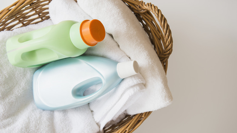 Two bottles of detergent in a wicker basket with a towel