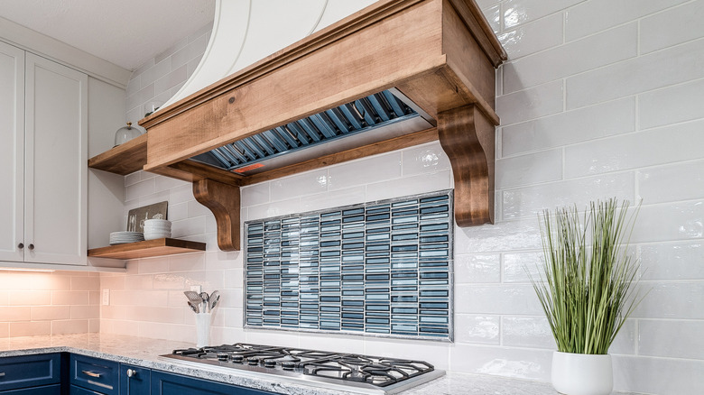 Wood corbels on a range hood to create contrasting color