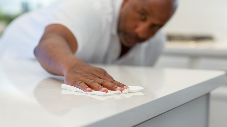 Man wiping quartz countertop