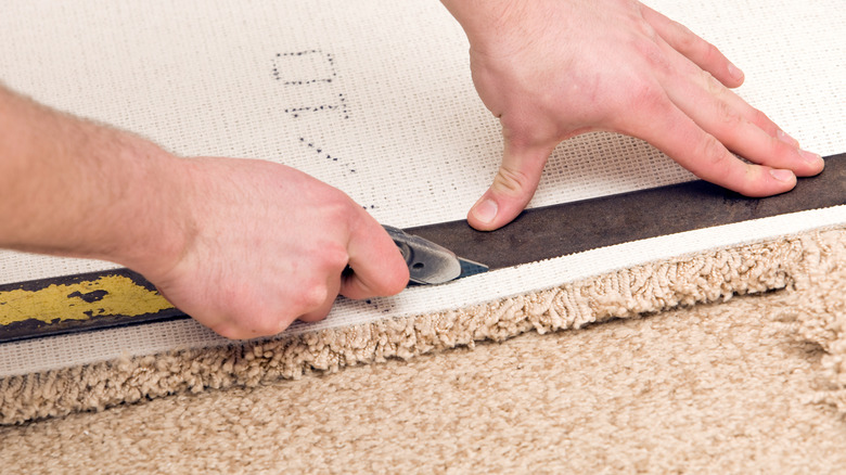 Someone installing and cutting carpet