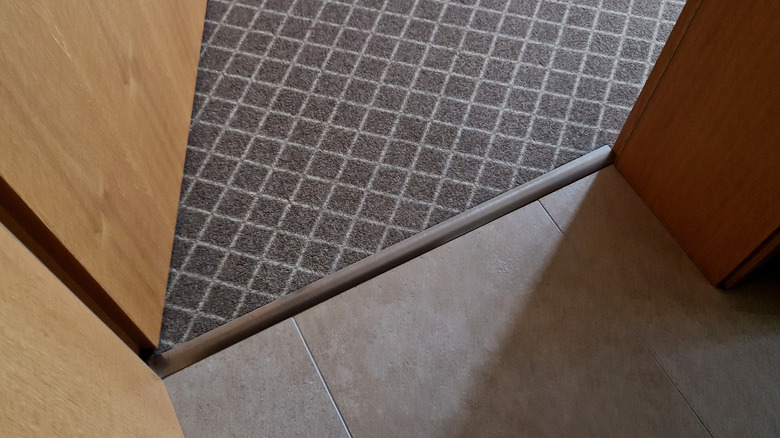 Metal transition strip being used between carpet and tile.