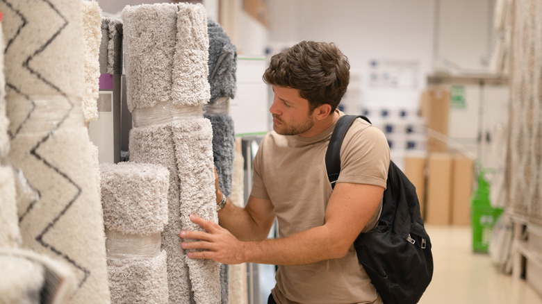 man looking at different carpets