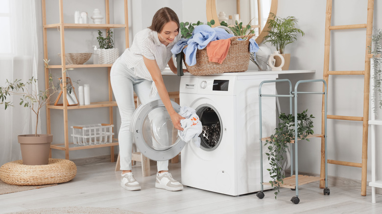 woman putting dirty clothes in washing machine