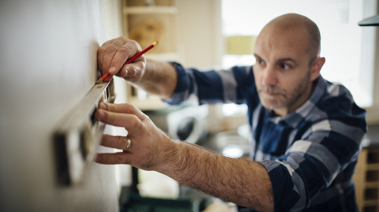 person measuring wall for shelf