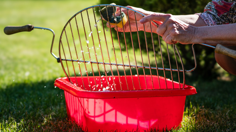 person cleaning grill in a red container