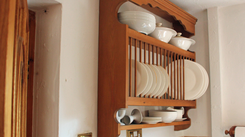 wooden wall plate rack with white ceramic plates and bowls