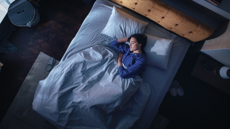 Woman sleeping in a dark bedroom.