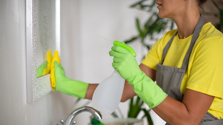 Woman cleaning mirror