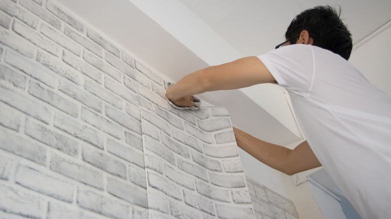 man applying wallpaper