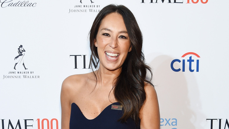 Joanna Gaines smiling in front of red carpet backdrop