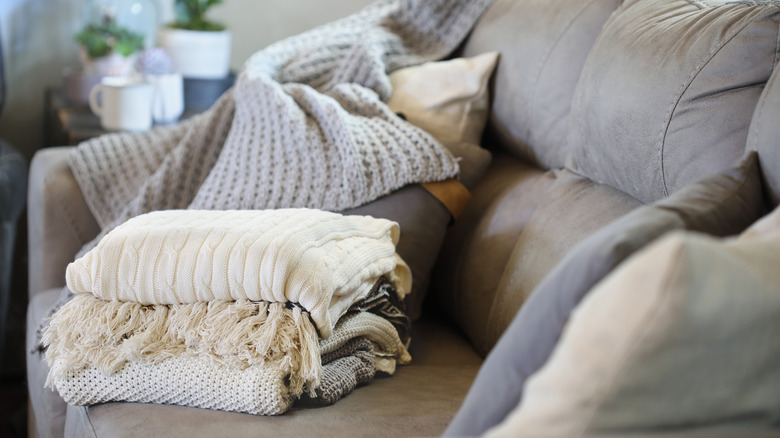 Several blankets stacked on a gray couch