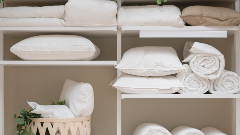 A linen closet with white linens